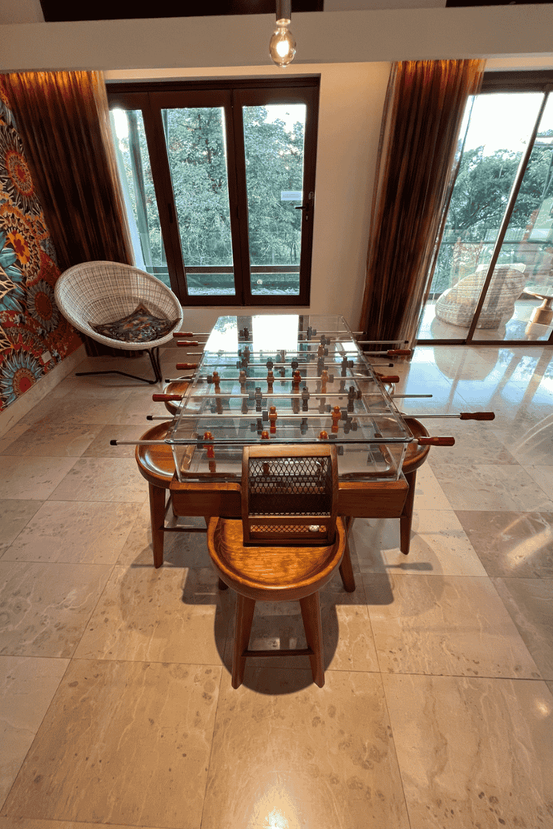 A glass table featuring a foosball table on top, complemented by a stylish minibar in the background.