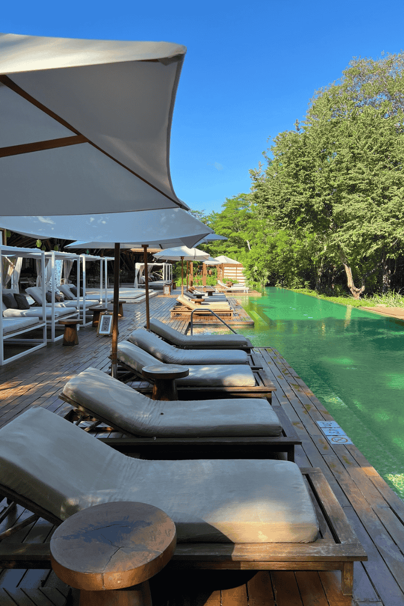 A bright sun shines over a serene pool, casting reflections on the water's surface.