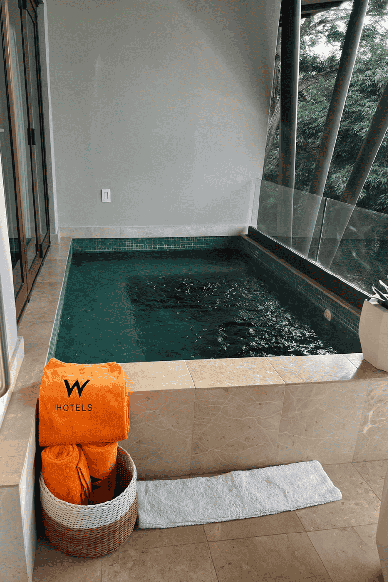 A stylish bathtub accompanied by a basket of towels, with an eye-catching orange towel placed on the rim.