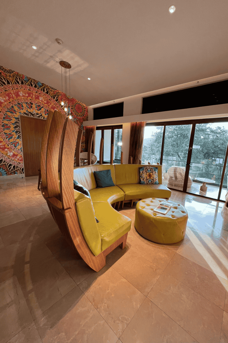 A vibrant living room featuring a colorful wall mural, a yellow couch, and a stylish minibar for entertaining guests.